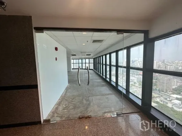 办公空间 出租 - 玻璃双开门通向长廊，整面落地窗俯瞰高层城市景观。