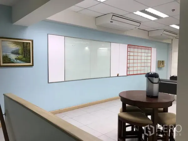 Office Space for rent in Khlong Toei, Bangkok - Breakout area with round table and stools, wall whiteboards and ceiling air-conditioning units.
