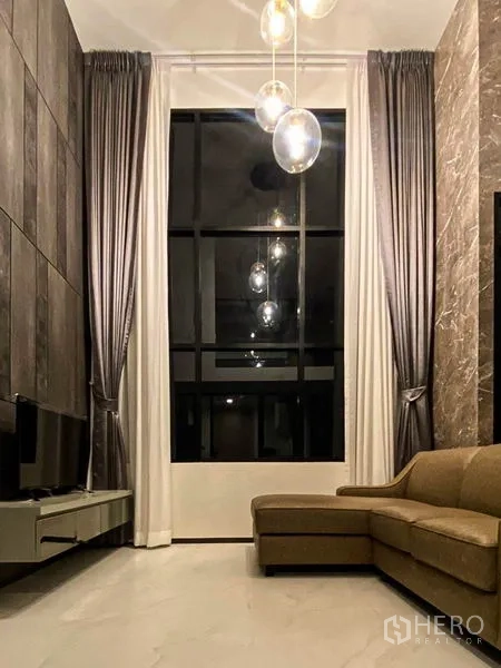 公寓 出租在Sathon, Bangkok - 时尚起居区，球形吊灯、高挑窗帘与整面落地窗。