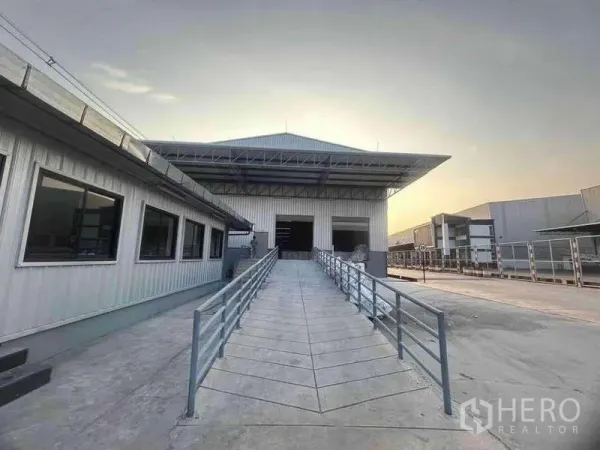 货栈 出租在Si Racha, Chon Buri - 现代仓库正面视角，宽阔通道坡道与有顶装卸区，旁连办公楼