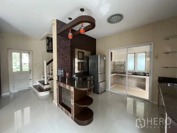 บ้าน ให้เช่าในLat Krabang, Bangkok - พื้นที่ครัวกับบันได มีบาร์อาหารเช้าและประตูกระจกบานเลื่อนไปครัวไทย