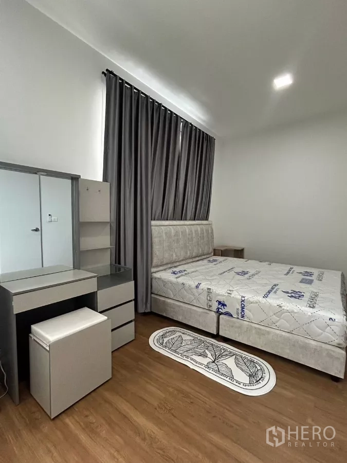 Townhouse for rent in Bang Phli, Samut Prakan - Master bedroom view of bed, vanity desk and floor-to-ceiling curtains.