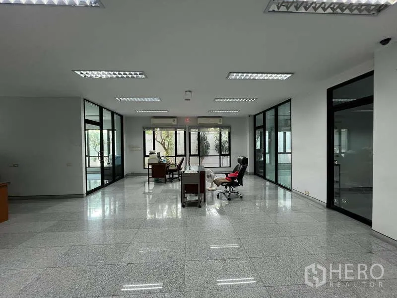 Office Space for sale in Bang Na, Bangkok - Expansive open-plan office with glass walls separating work zones.