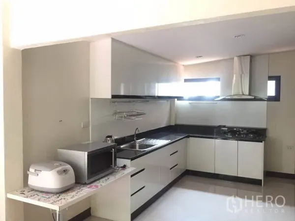 独立式住宅 出租 - 现代L型厨房，白色橱柜、黑色台面与抽油烟机。