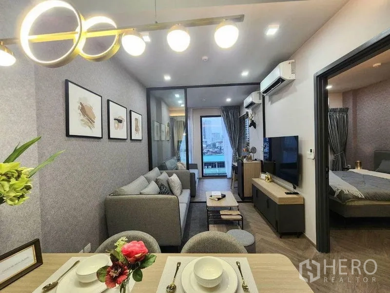 Condominium for rent in Bang Rak, Bangkok - Open-plan dining and living area with TV wall and sliding door to the balcony.