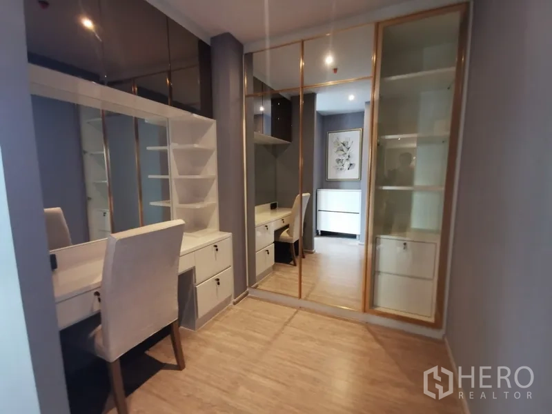 Condominium for rent or sale in Watthana, Bangkok - Dressing room and study area with built-in desks, shelving, and gold-framed mirrored wardrobes.