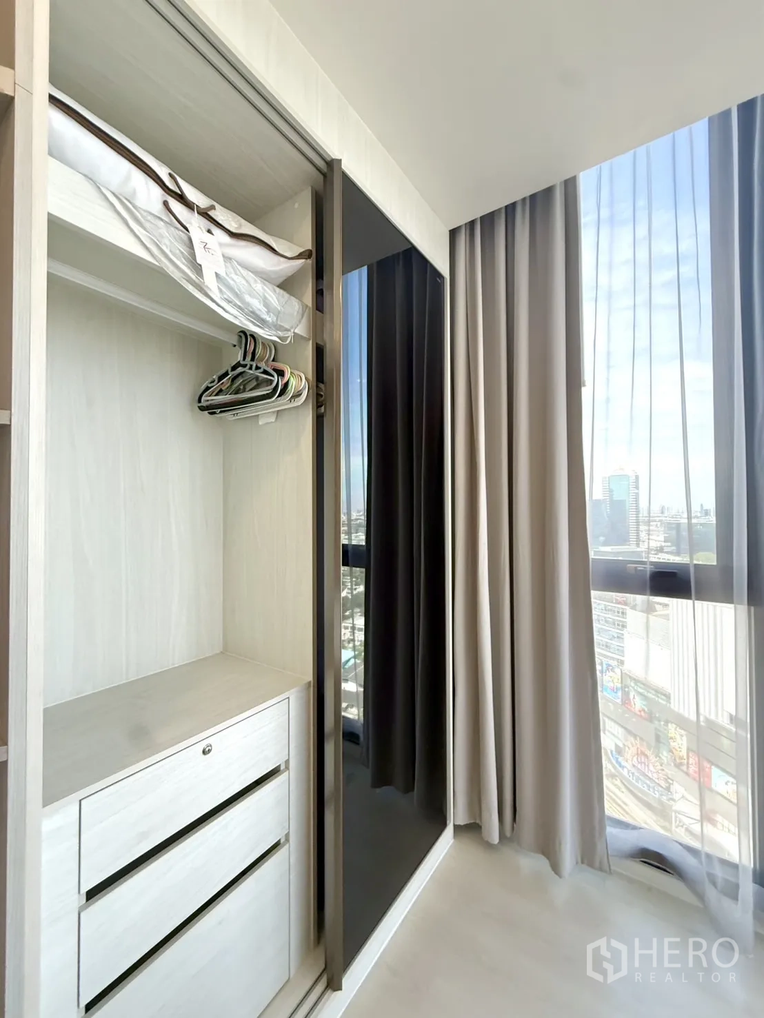 Condominium for sale in Chatuchak, Bangkok - Sliding wardrobe open to reveal drawers beside a window.