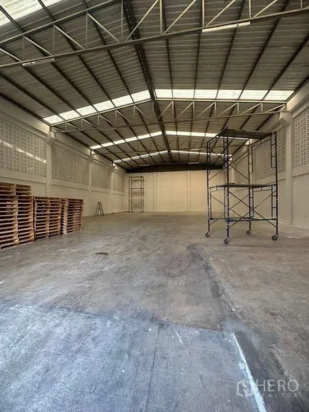 货栈 出租在Suan Luang, Bangkok - 开阔的工业仓储区，展示钢结构屋顶和可移动脚手架。
