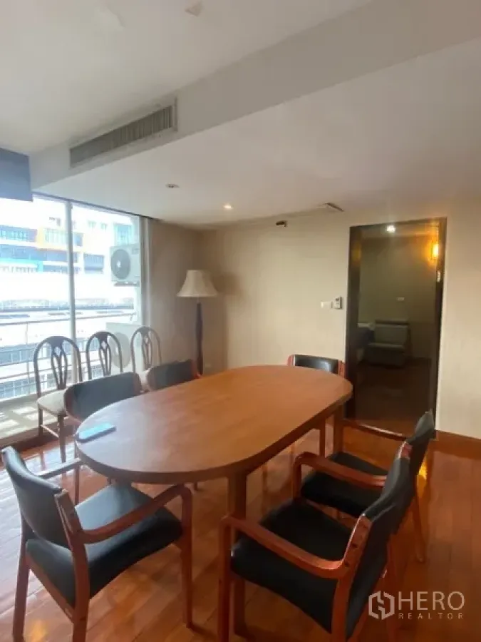 公寓 出租或出售在Watthana, Bangkok - 采光良好的餐区，配椭圆木桌、皮椅、木地板与大窗户城市景观