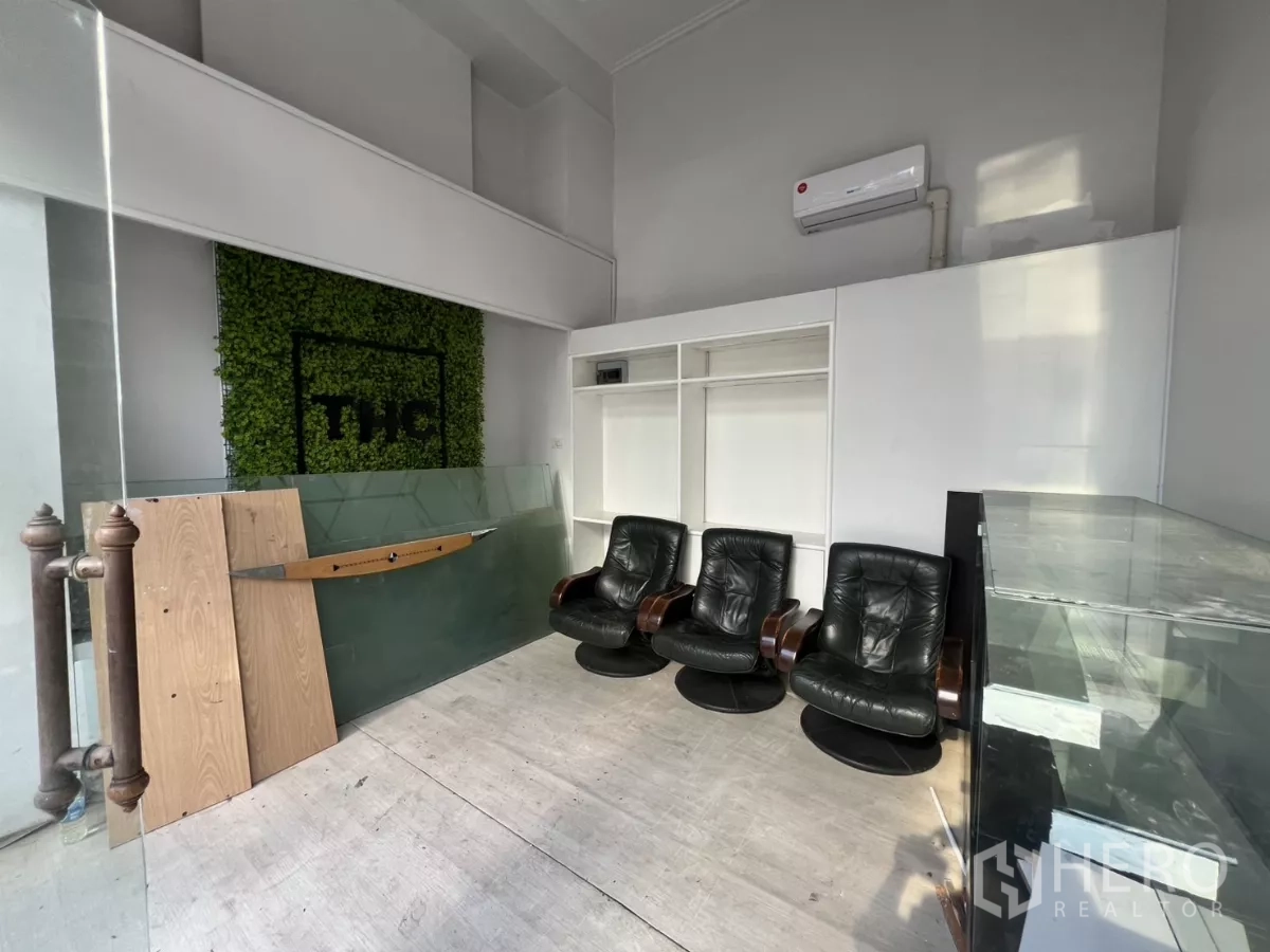 พื้นที่ขายปลีก ให้เช่า - โซนโชว์รูมมีผนังตกแต่งสีเขียว ตู้บิวท์อิน ตู้โชว์กระจก และประตูกระจกด้านหน้า