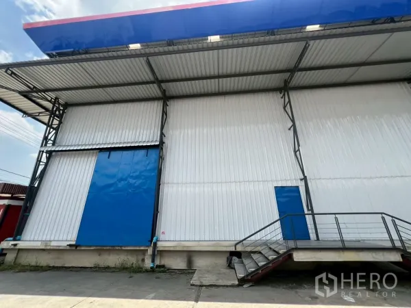 Warehouse for rent in Lat Krabang, Bangkok - Dock-level loading platform with blue rolling door and a pedestrian side door under a wide canopy.