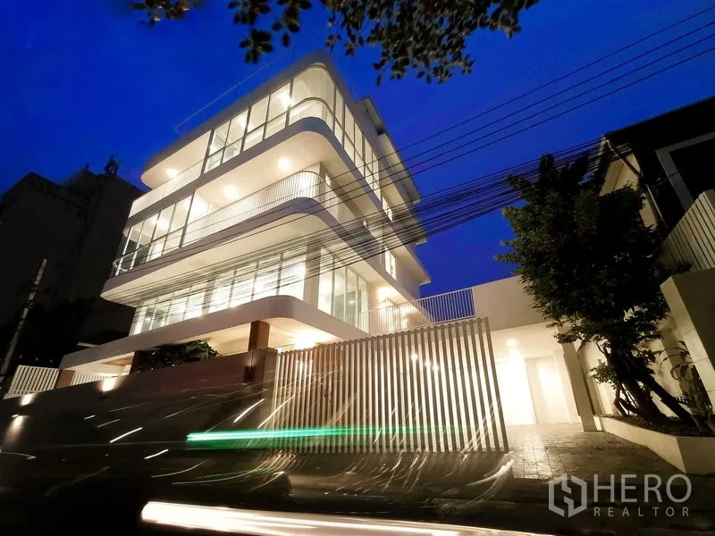 Home Office for sale in Suan Luang, Bangkok - Nighttime exterior of an illuminated modern building along a quiet street.