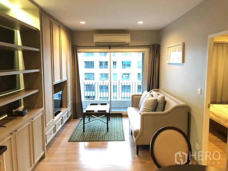 คอนโด ให้เช่าในPathum Wan, Bangkok - ห้องนั่งเล่นสว่างพร้อมชั้นบิลท์อิน ทีวี โซฟา และประตูกระจกเปิดสู่ระเบียง