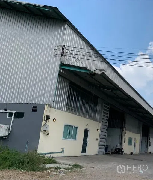 货栈 出租在Khlong Luang, Pathum Thani - 金属外墙仓库外观，带装卸雨棚、办公窗与车道，位于Khlong Luang。