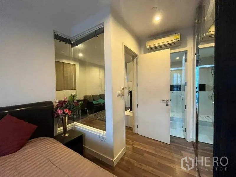 Condominium for sale - Bedroom corner with glass partition to the living room, doorway to the bathroom, and wall air conditioner.