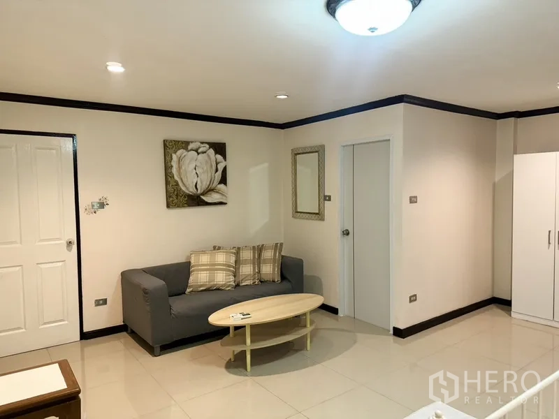 联排别墅 出租在Prawet, Bangkok - 主卧休息角，配小沙发与两扇室内门。