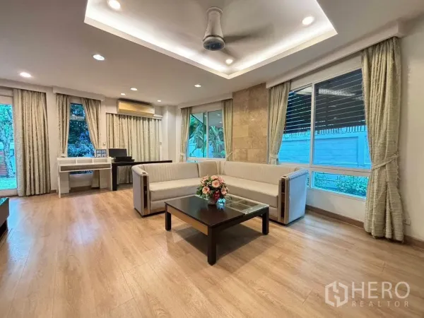 独立式住宅 出租在Bang Kapi, Bangkok - 采光充足的客厅，L形沙发、木地板与落地窗