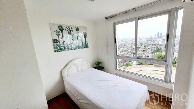 Condominium for sale in Bang Kho Laem, Bangkok - Corner bedroom with single bed and wide window overlooking the city.