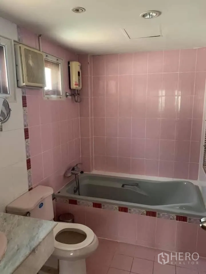 联排别墅 for rent in Watthana, Bangkok - 粉色瓷砖浴室，带浴缸、坐便器和热水器。