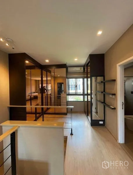 Townhouse for rent in Yan Nawa, Bangkok - Upper-floor corridor with glass wardrobes, shelving, and access to a bathroom.