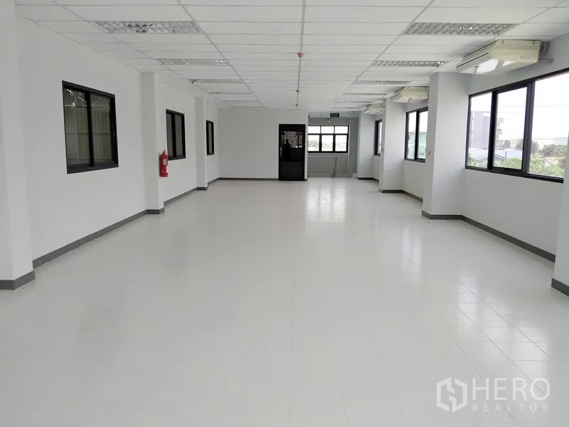 Factory for rent or sale in Samut Prakan - Open‑plan office level with windows on both sides and white tile flooring.