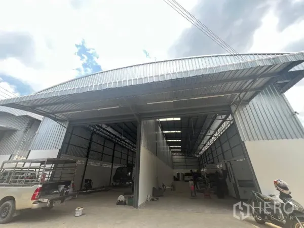 货栈 出租在Khlong Sam Wa, Bangkok - 高挑空仓库的外立面斜视图，配宽幅卷闸门与金属雨棚，适合卡车进出。