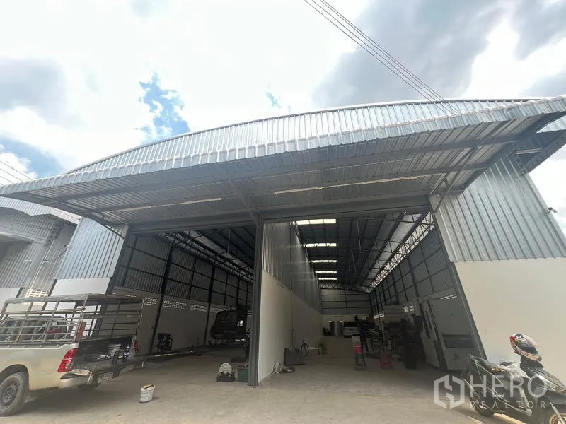 货栈 出租在Khlong Sam Wa, Bangkok - 高挑空仓库的外立面斜视图，配宽幅卷闸门与金属雨棚，适合卡车进出。