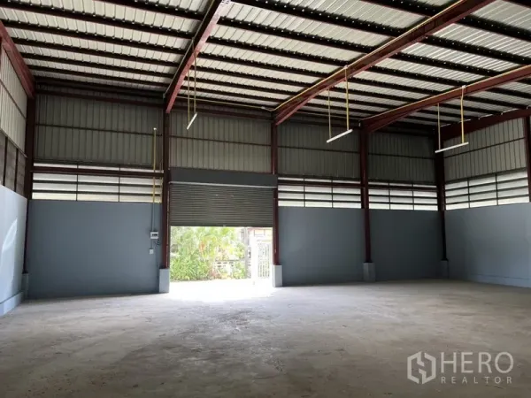 Warehouse for rent in Khlong Sam Wa, Bangkok - Spacious warehouse interior with high steel roof, roller shutter door, and ample natural light.