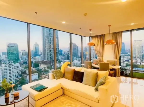 Condominium for rent or sale in Sathon, Bangkok - L-shaped sofa in a corner lounge with wraparound glass and skyline views.
