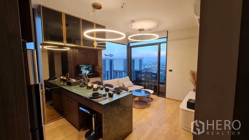 Condominium for rent in Watthana, Bangkok - Kitchen and living area with island dining, ring pendant lights, and balcony views.