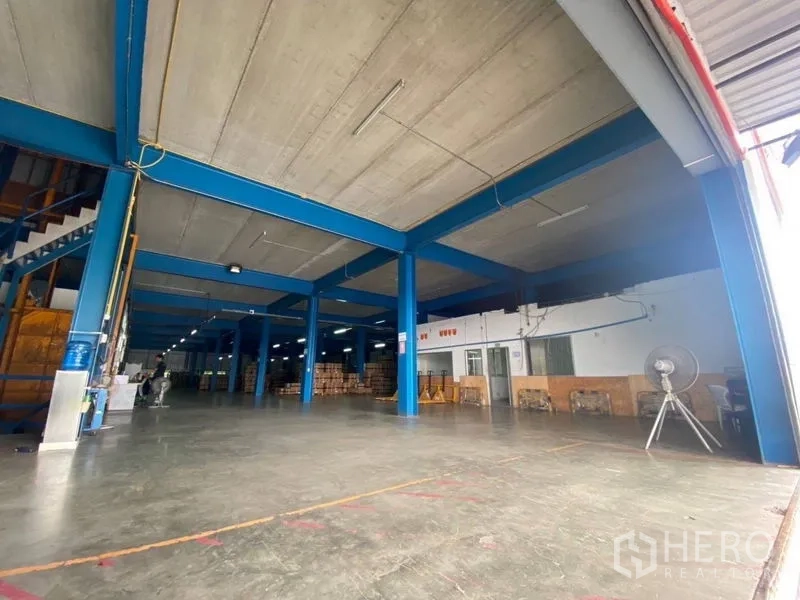 Factory for rent or sale in Lam Luk Ka, Pathum Thani - Spacious production floor with high ceiling, blue steel columns and concrete slab.