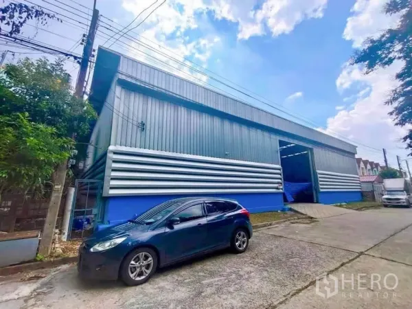 คลังสินค้า ให้เช่าในThanyaburi, Pathum Thani - ด้านหน้าโกดังพร้อมประตูขนถ่าย เปิดโล่ง ฐานสีน้ำเงิน และทางรถเข้าออกสะดวก