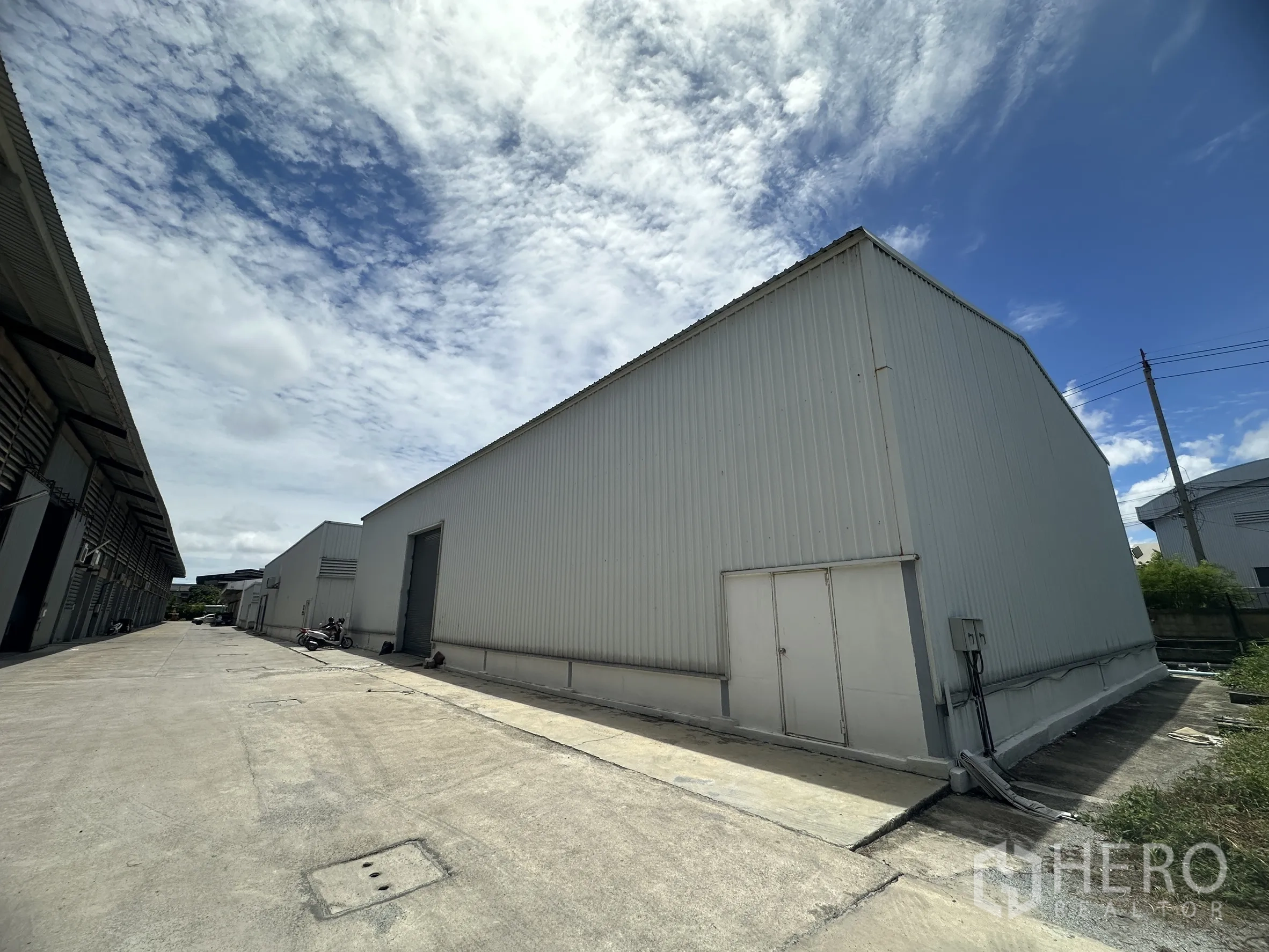 工厂 for rent in Mueang Samut Prakan, Samut Prakan - 工厂侧立面与宽阔通道，可见服务门和电箱。
