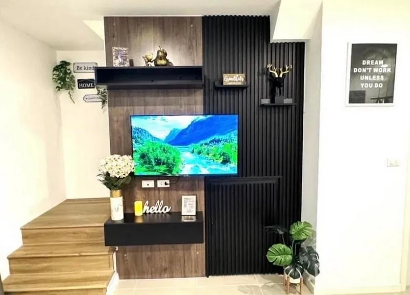 Townhouse for rent - Close-up of contemporary TV wall with shelves and decor beside the stairs.
