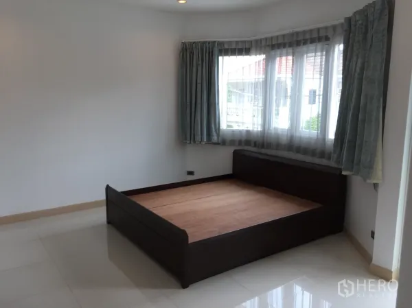 ทาวน์เฮาส์ ให้เช่าในDin Daeng, Bangkok - ห้องนอนสว่าง มุมหน้าต่างบานใหญ่ ผ้าม่านโปร่ง และเตียงไม้สีเข้ม พื้นกระเบื้องเงา