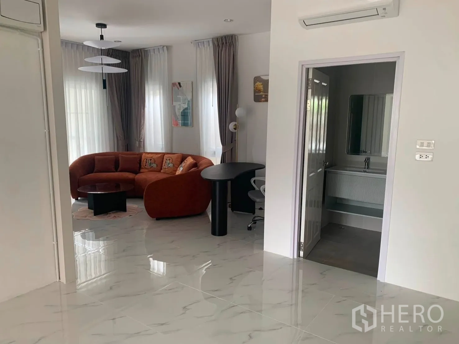 Detached House for rent in Bang Phli, Samut Prakan - Bright living space with an orange curved sofa, desk and nearby bathroom.