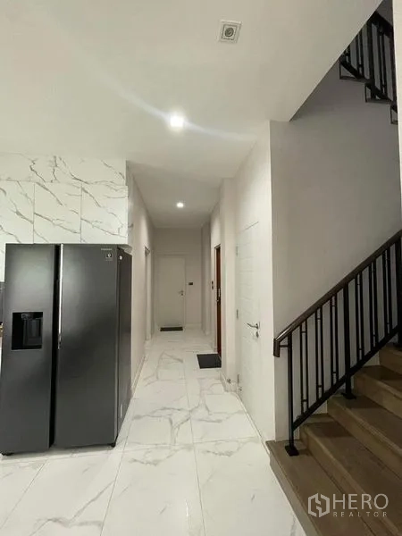 独立式住宅 出售在Bueng Kum, Bangkok - 厨房旁走廊，石纹地面，深色冰箱与上楼楼梯。