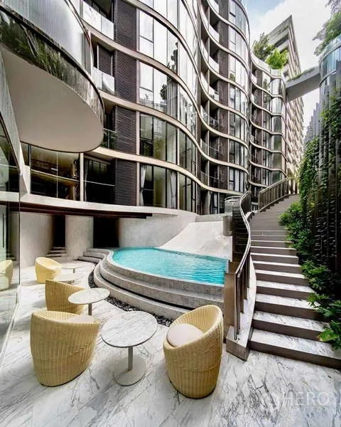 Condominium for rent - Poolside terrace with wicker chairs, marble flooring and steps beside the building’s flowing facade.