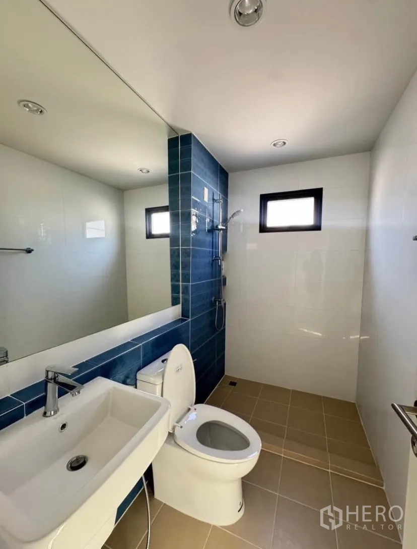 บ้านเดี่ยว for rent or sale in Lat Krabang, Bangkok - ห้องน้ำสไตล์โมเดิร์น ผนังกระเบื้องสีน้ำเงิน อ่างล้างหน้า โถสุขภัณฑ์ และฝักบัวแบบเปียกแห้ง พร้อมหน้าต่าง