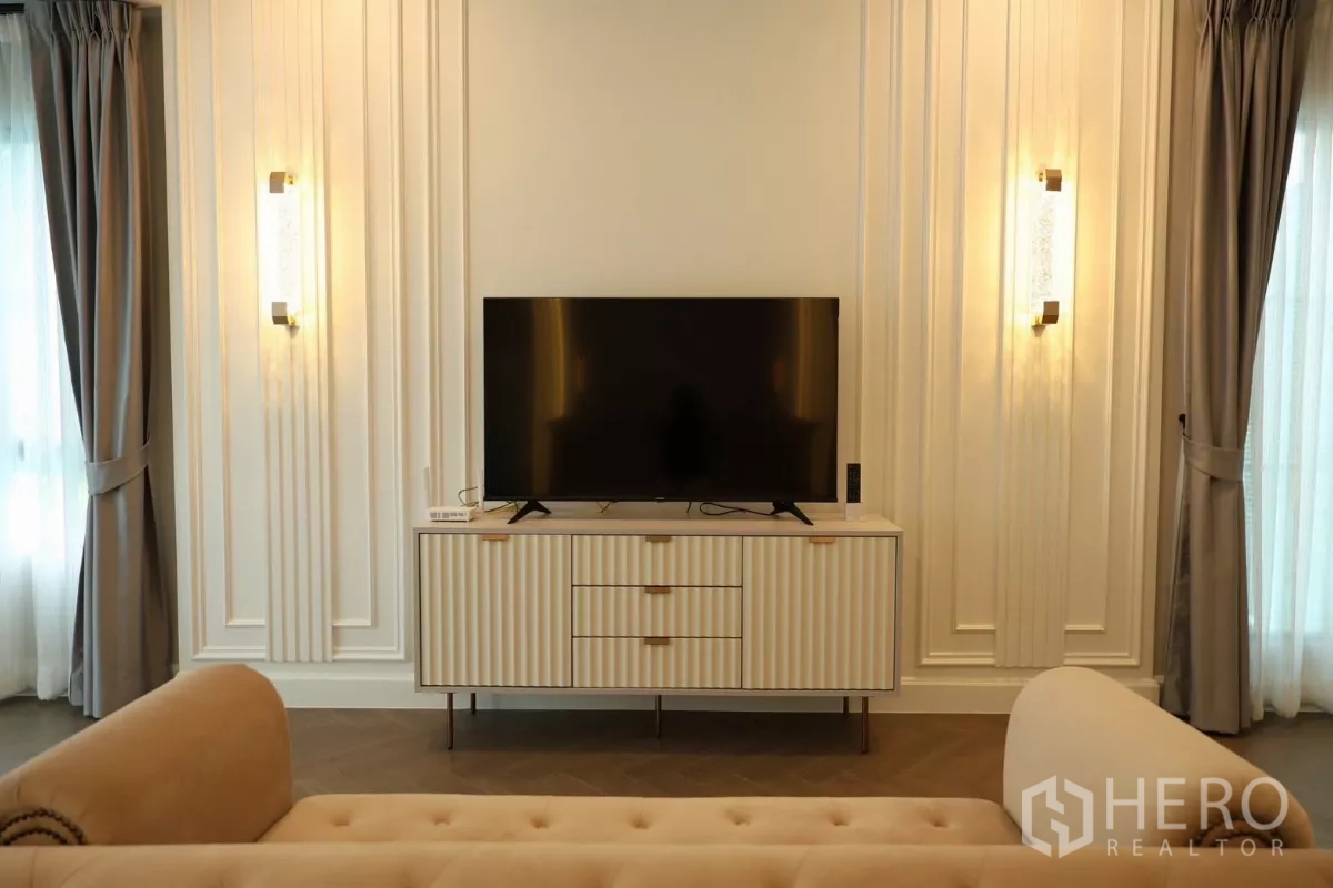 Detached House for rent or sale in Saphan Sung, Bangkok - Cozy bedroom TV corner with wall sconces and a ribbed console cabinet.
