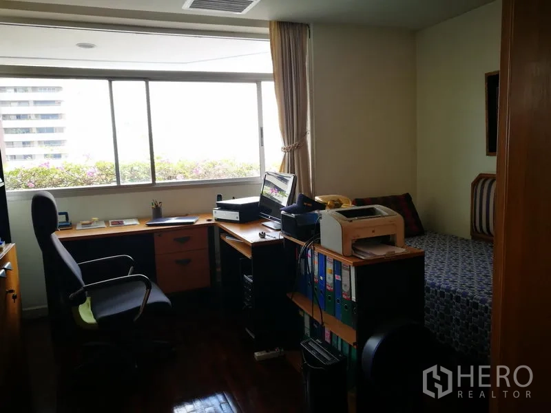 公寓 出租或出售在Watthana, Bangkok - 家用书房，长书桌、收纳柜与靠窗单人床。