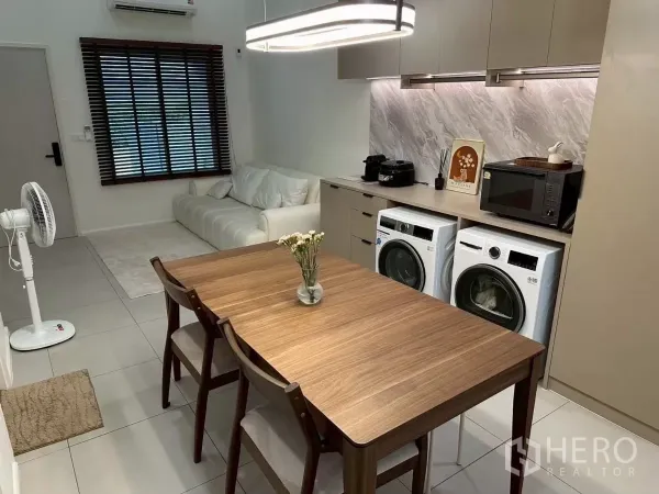 Townhouse for rent in Saphan Sung, Bangkok - Dining area facing a large window and sofa, with under-cabinet lighting and countertop appliances.