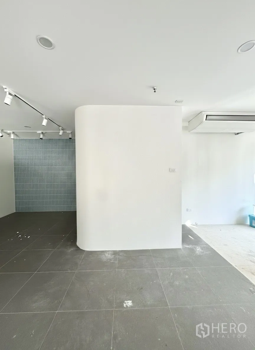 พื้นที่ขายปลีก ให้เช่า - ผนังโค้งตกแต่งคู่กับกระเบื้องสีเทาและผนังกระเบื้องสีฟ้าภายใต้รางไฟ