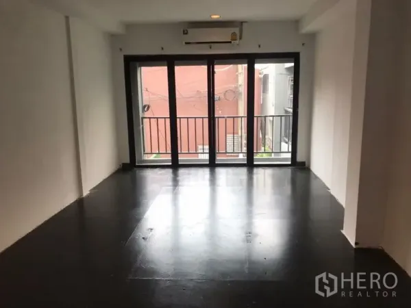 Home Office for rent or sale in Khlong Toei, Bangkok - Open-plan home office room with black flooring, white walls and sliding glass doors to a small balcony.