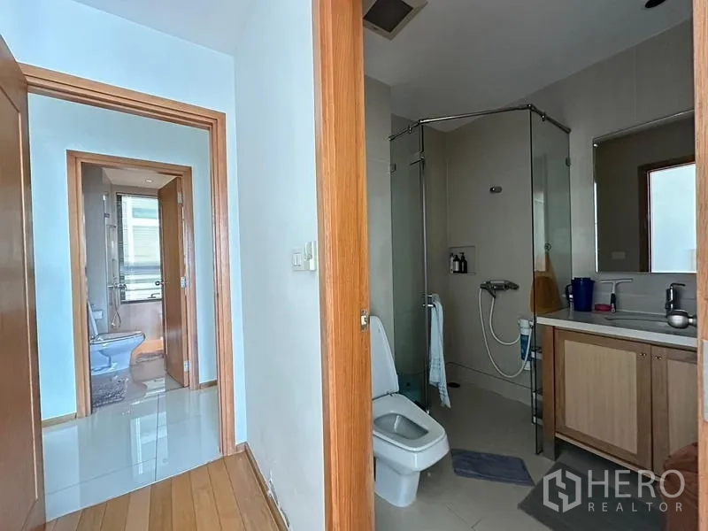 คอนโด ขายในKhlong Toei, Bangkok - ห้องน้ำพร้อมตู้อาบน้ำกระจก โถสุขภัณฑ์ และอ่างล้างหน้า; ทางเดินสู่ห้องน้ำอีกห้อง