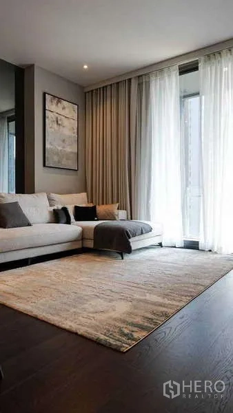 Condominium for rent or sale in Watthana, Bangkok - Spacious lounge with sectional sofa, area rug and sliding door to balcony.