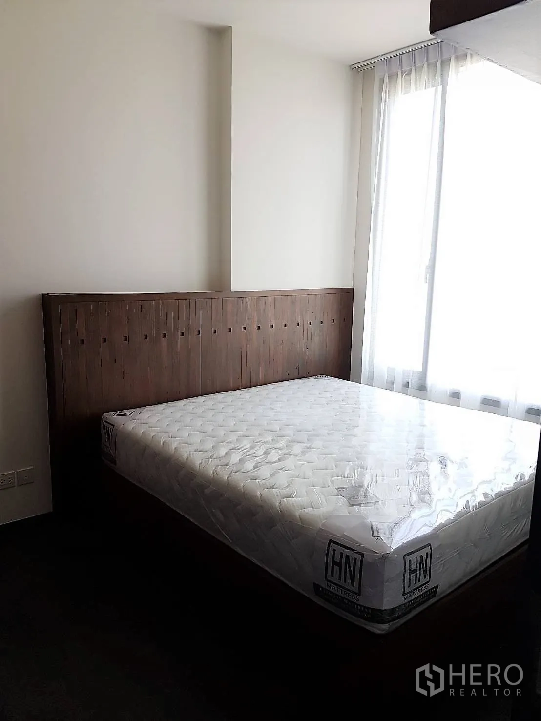Condominium for rent or sale in Watthana, Bangkok - Cozy bedroom with wooden headboard and a large window bringing in natural light.