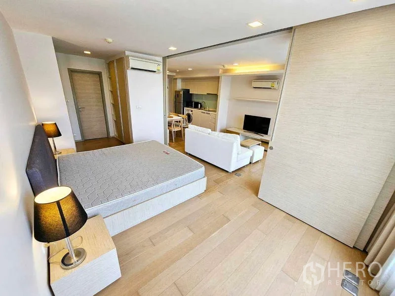 Condominium for rent - Bedroom with bedside lamps and sliding door looking toward living room and kitchen.