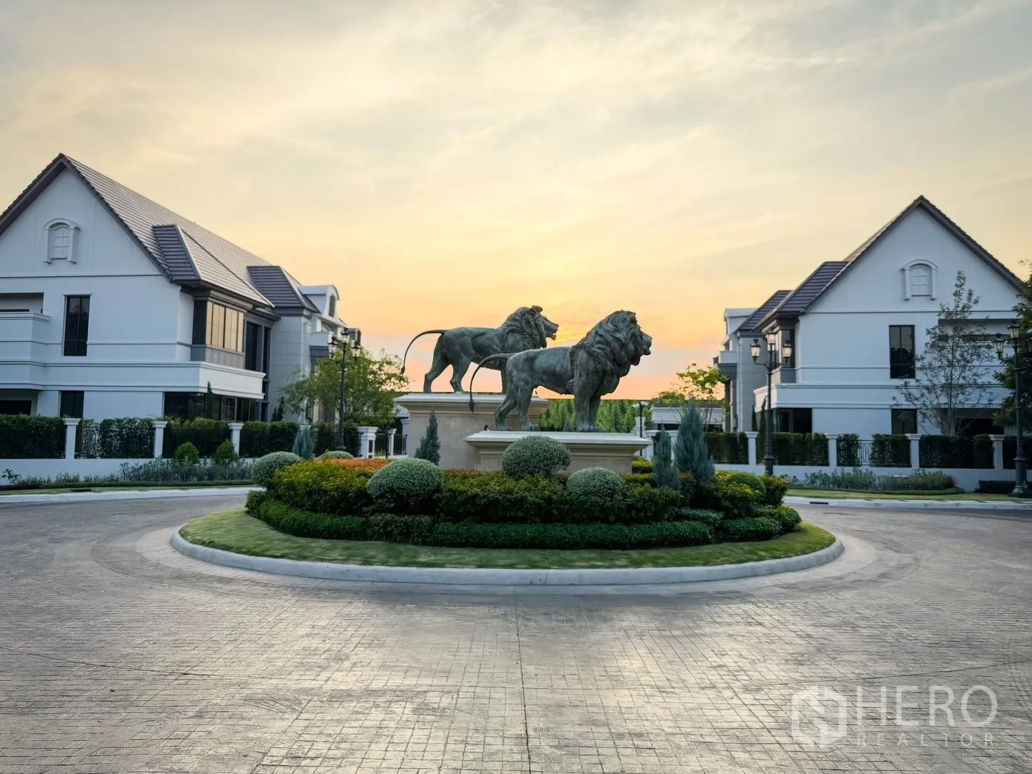 บ้านเดี่ยว for rent in Bang Khen, Bangkok - วงเวียนหน้าหมู่บ้าน รูปปั้นสิงโตล้อมรอบด้วยบ้านหรู บรรยากาศพระอาทิตย์ตก.