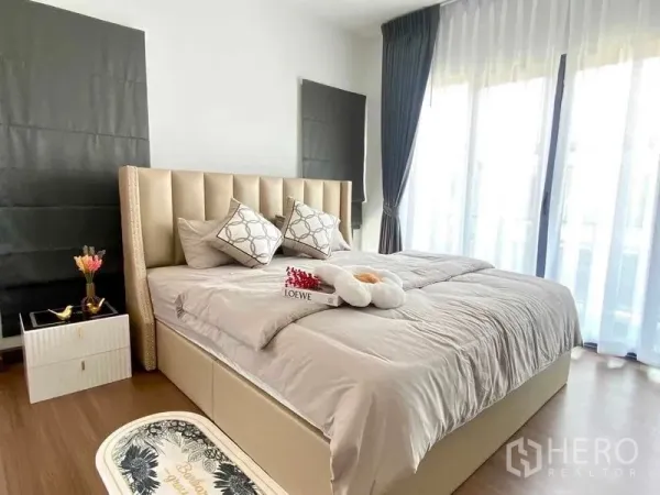 Detached House for rent or sale in Bang Phli, Samut Prakan - Bright master bedroom with upholstered bed, wood flooring and sheer floor-to-ceiling curtains.